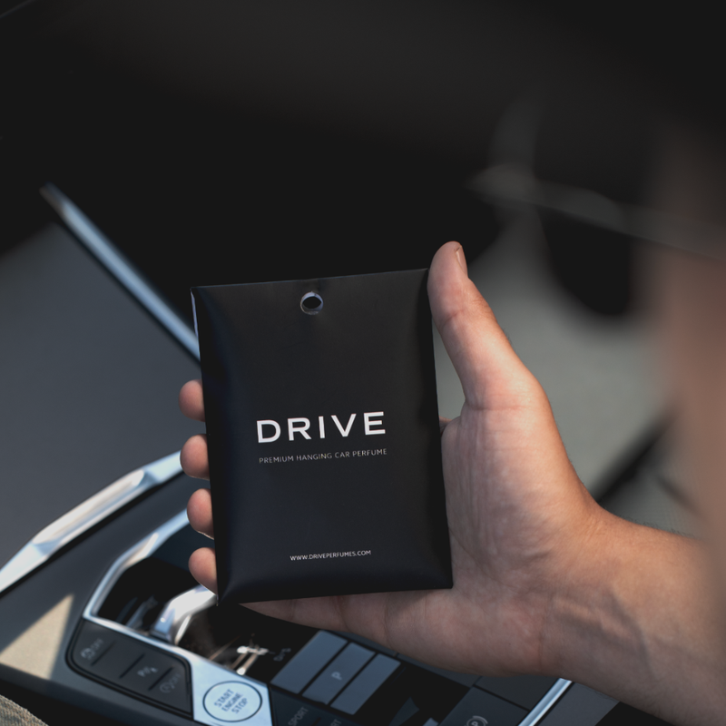 Hand holding a Drive car perfume envelope inside a car