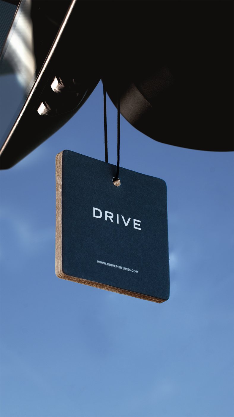 Drive hanging car perfume card on a rearview mirror against a blue sky